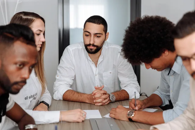 A diverse team of adults collaborating in an office meeting, showcasing teamwork and professionalism. Choosing between a customer forum and a professional group