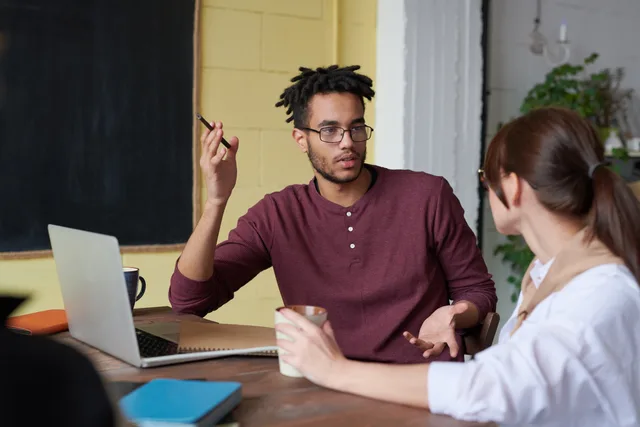Two colleagues engaged in a collaborative discussion during a team meeting at the office. Customer feedback through communities