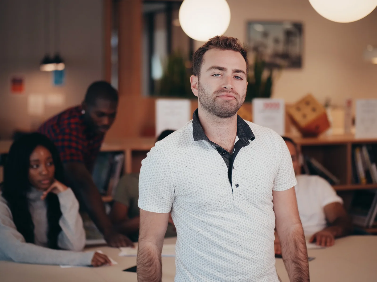 A diverse group of adults engaged in a meeting in a modern office setting.