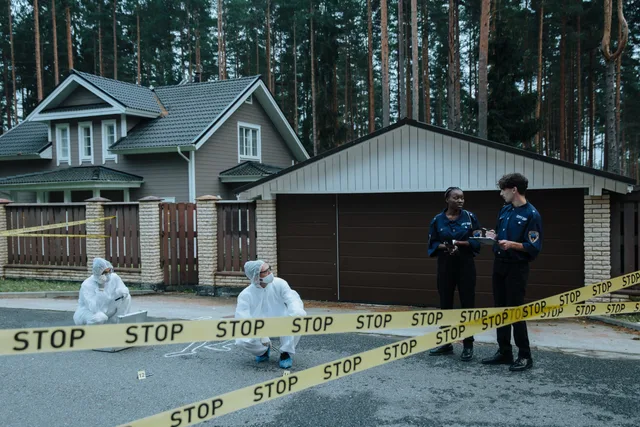 Crime scene investigation in progress outside a suburban house with police officers and forensic experts. Handling community conflict and incidents