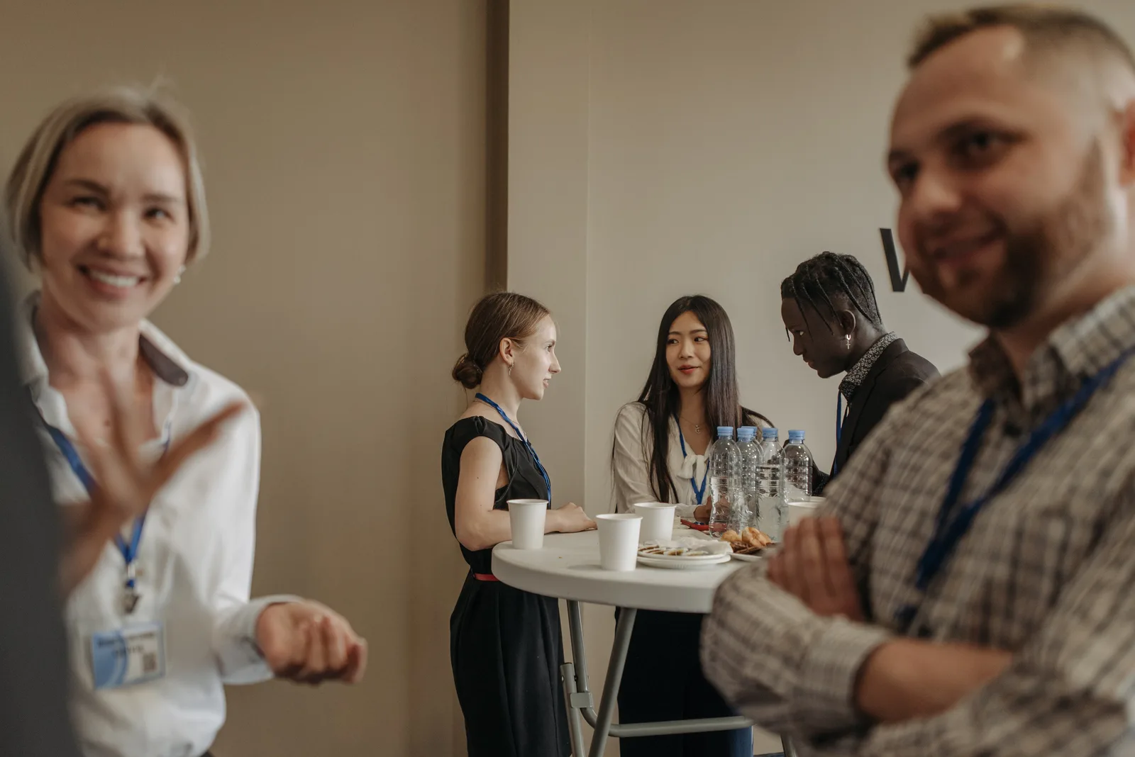A diverse group of adults networking during a business conference break with refreshments.