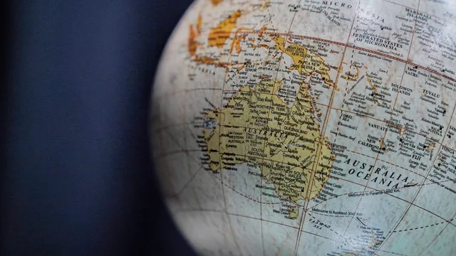 A detailed close-up of a vintage globe focusing on Australia and Oceania, highlighting geographical textures. Planning coverage across time zones